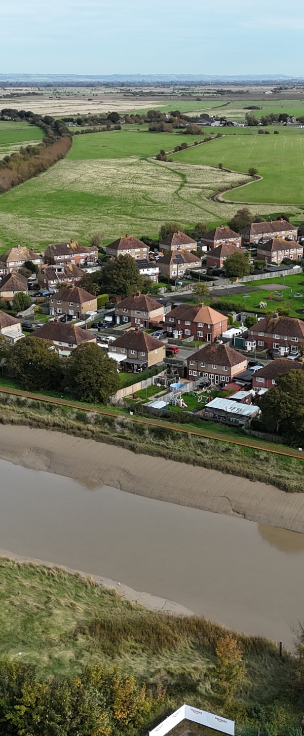 Picture of a river running in front of houses. Rother Tidal Walls 