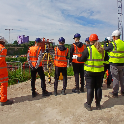 People in highvis on a site tour of the New Wear high-level Footbridge sign.