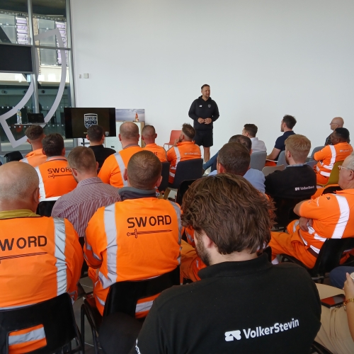 People in highvis watching a presentation. 