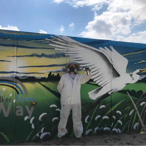 Picture of artist stood in front of the mural.