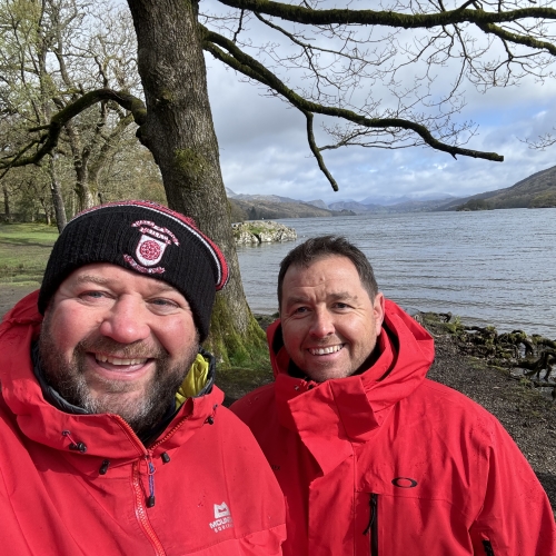 Two people stood in the woods smiling.
