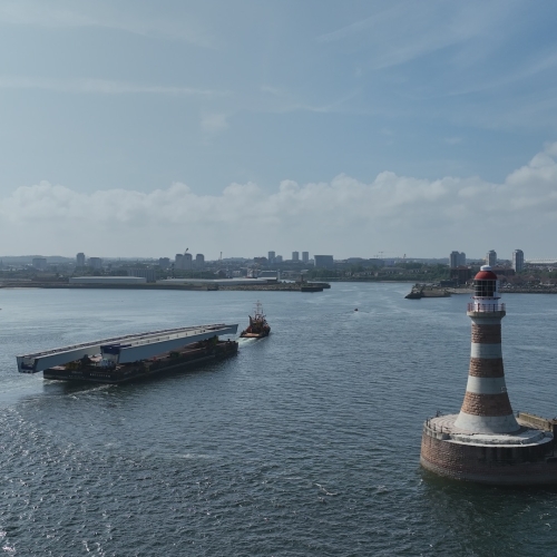bridge section on barge travelling on water out of a port