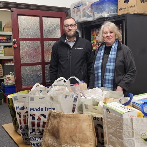 Man and women stood by table with food donations