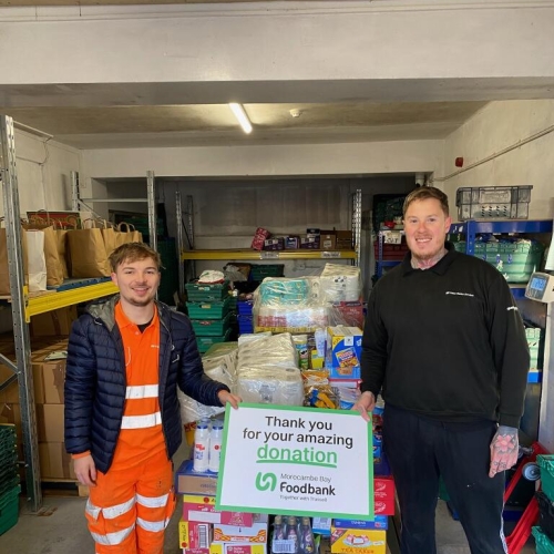 two men stood by crate with food donations on