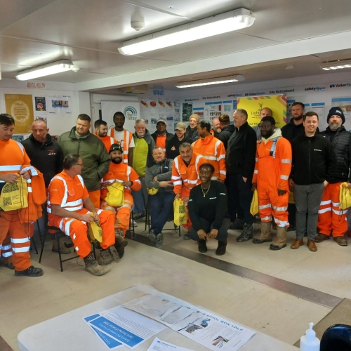 Group of people stood in a huddle, smiling at the camera.