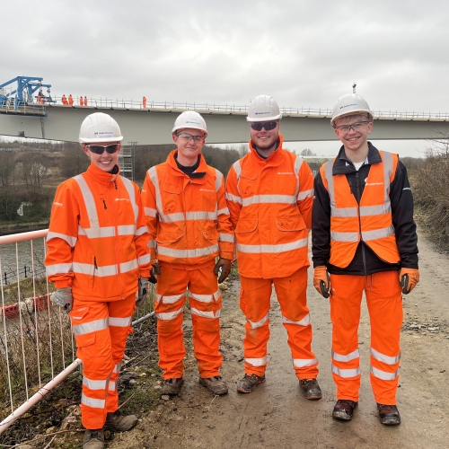 Four people stood in front of a bridge.