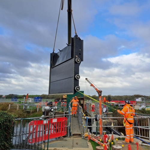 two people on a construction site lifting a part of a gate into place.