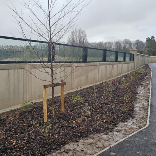 Brick wall with glass panels on top alongside a river