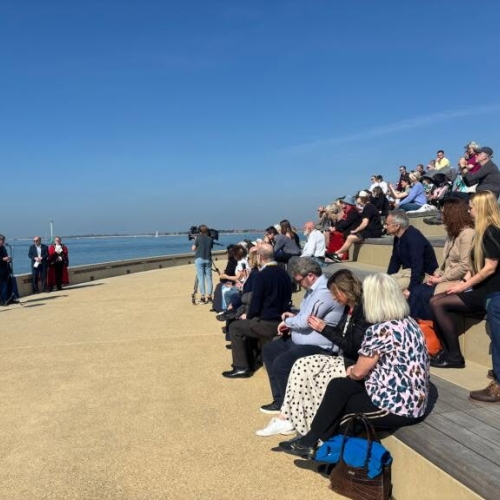 People sat on seafront promenade with blue skies