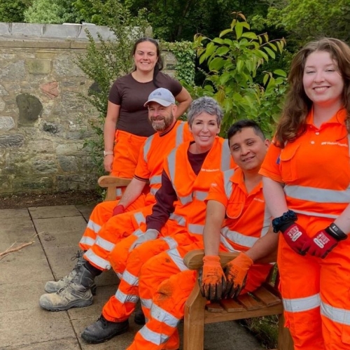 Team in orange PPE sat on a bench in a community garden in Sunderland