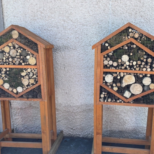Two bug houses made of wood with logs and twigs inside