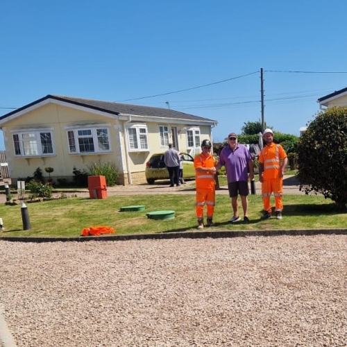People stood on grass outside a carpark.