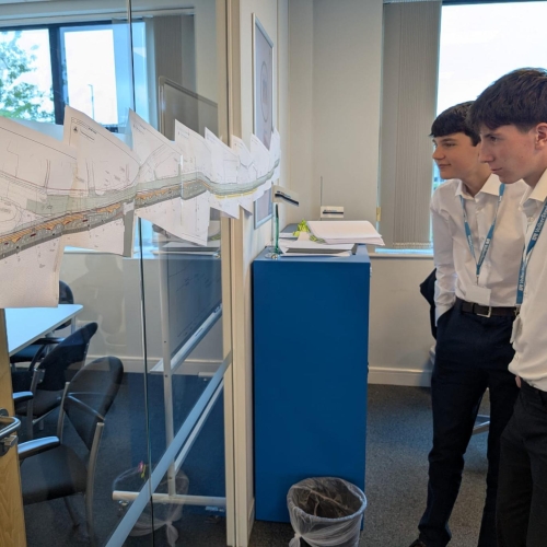 Two buys in white shirts looking at construction drawings