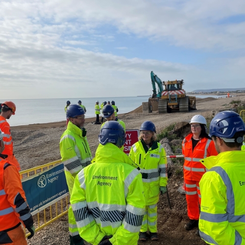People in high vis stood on a beach.