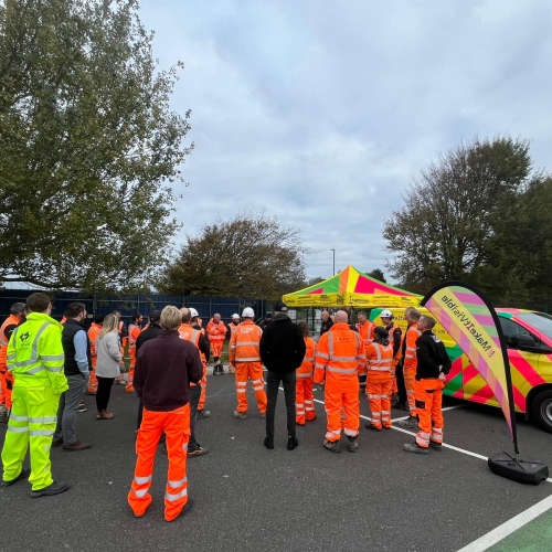 Group of construction workers in hi-vis workwear stood in a group in a car park
