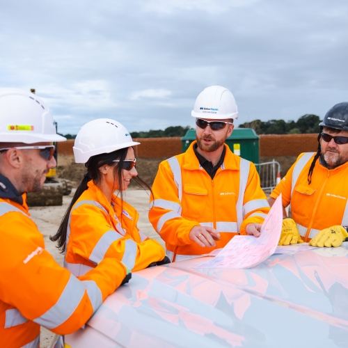 People in high vis stood around a drawing.