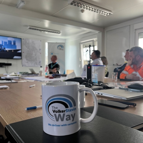 Picture of a Safety Ripple mug with people sat around a desk.