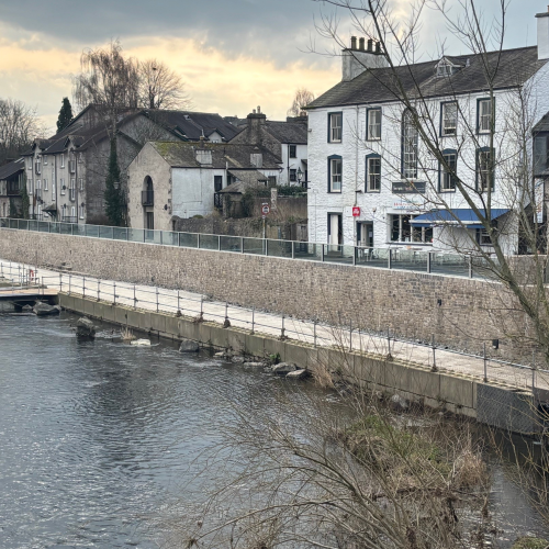 River showing glass panel flood wall looking onto housing