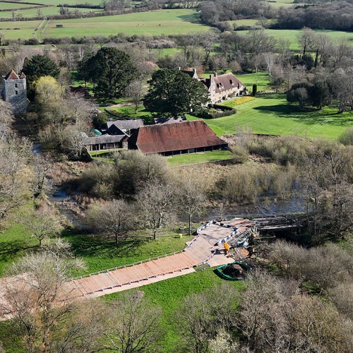 Aerial photo of fields and trees with houses and a church in the background and construction site in the foreground