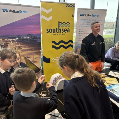 School children looking at information on a stand with banners beg=hind a table