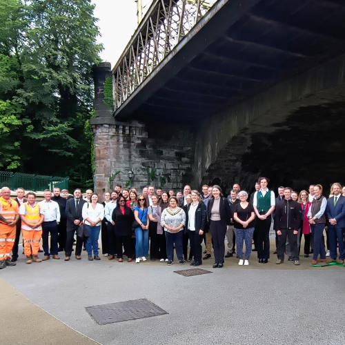 People stood in a group under a bridge.