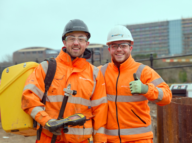 Tow men in orange hi-vis workwear on a construction site