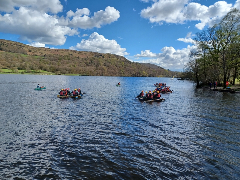Group of people sat in a homemade raft on a lake
