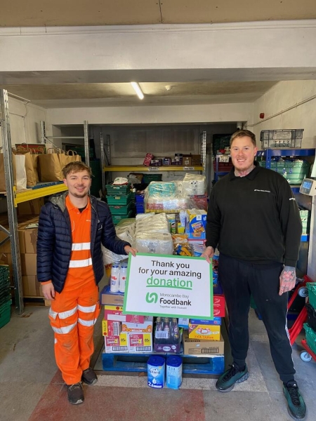 two men stood by crate with food donations on