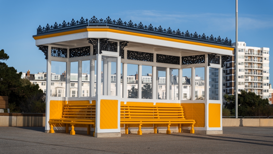 Covered shelter with bench seating around it painted in yellow