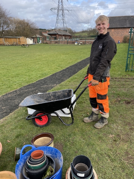 Male stood with donated wheelbarrow in school garden