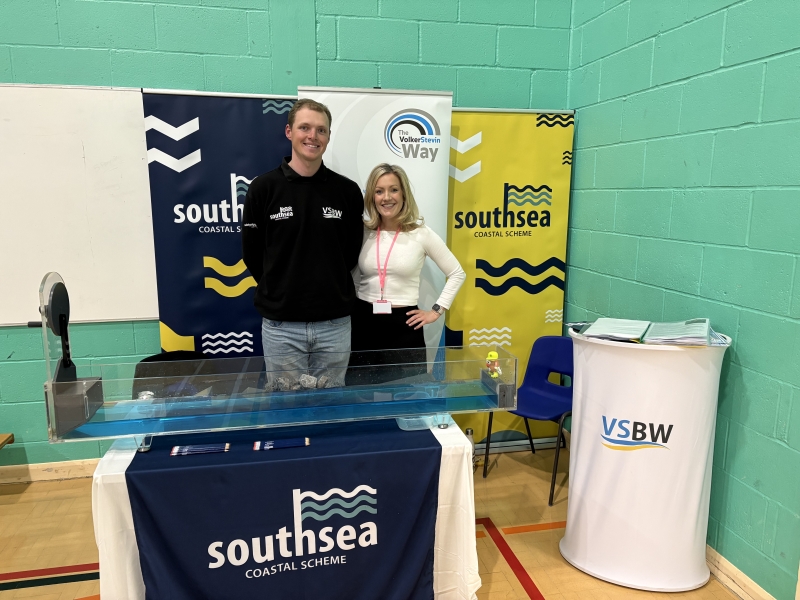 Man and women stood behind a table with banners behind