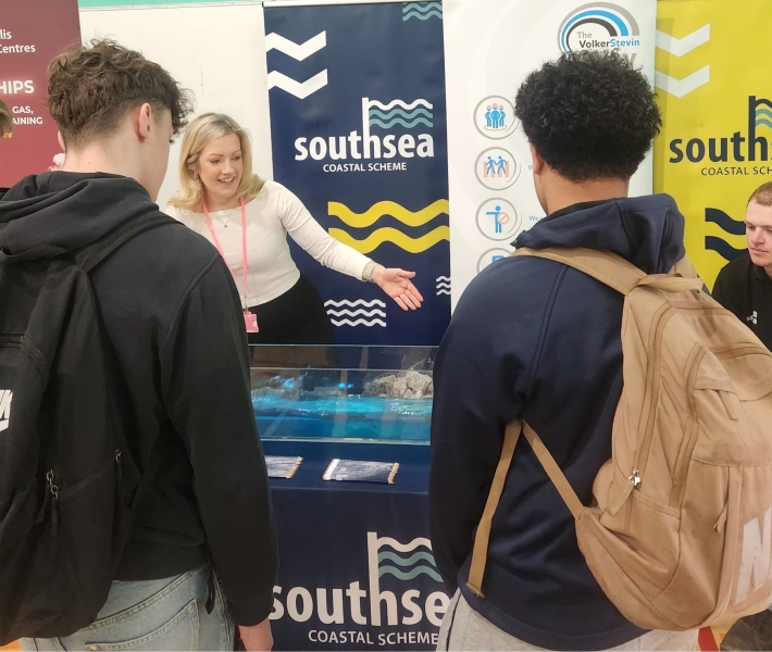 Students stood at a stand watching a wave machine demonstration