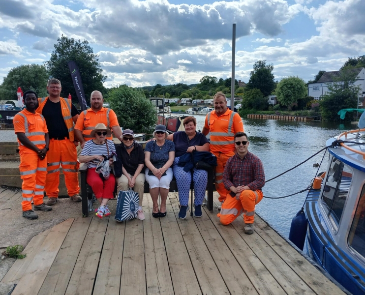 A group of men and women with construction workers sat by a river