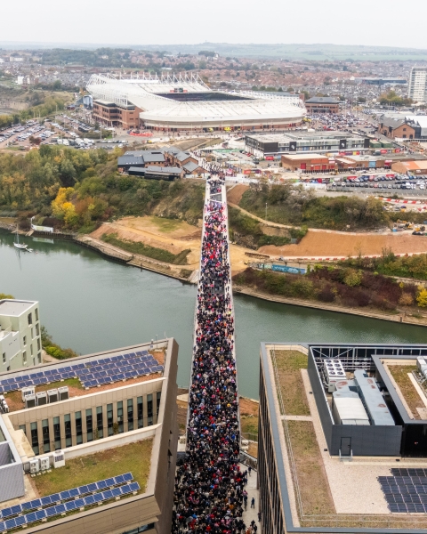 Keel Crossing opening - aerial image of a large group of people walking across the bridge