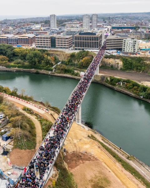 Keel Crossing opening - aerial image of a large group of people walking across the bridge