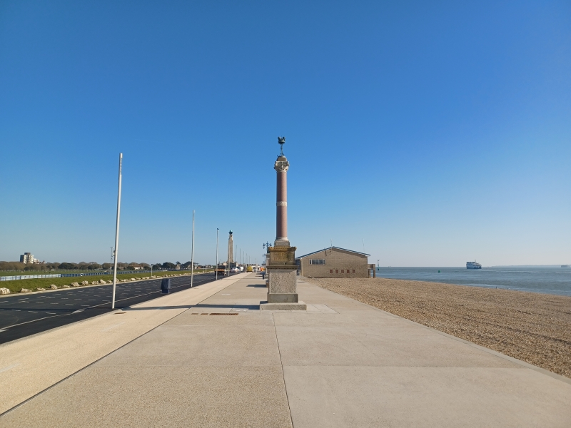 Promenade with beach to the right of the picture and monument in the background