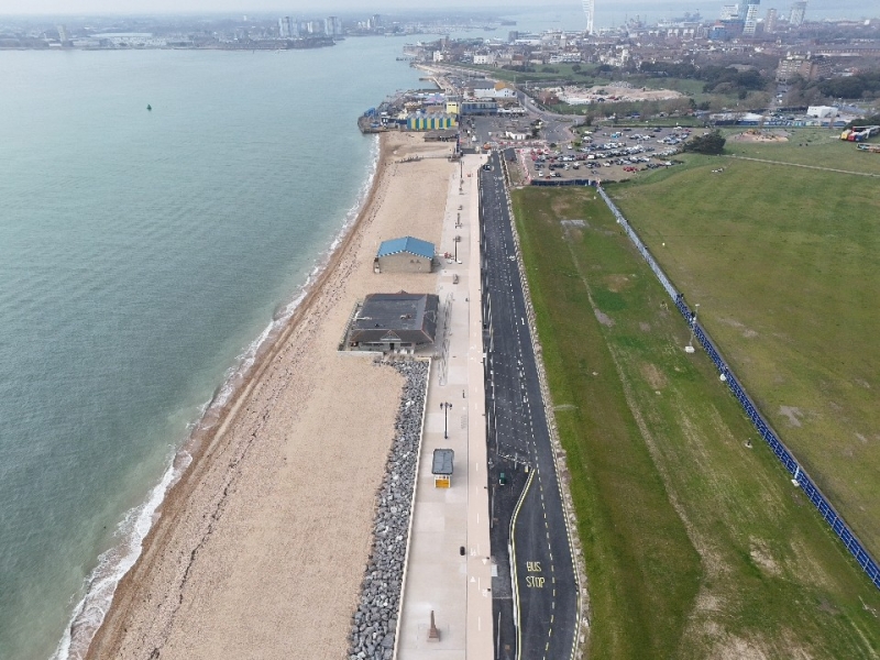Aerial view of promenade with the beach and sea to the left of the picture, green field to the right of the picture