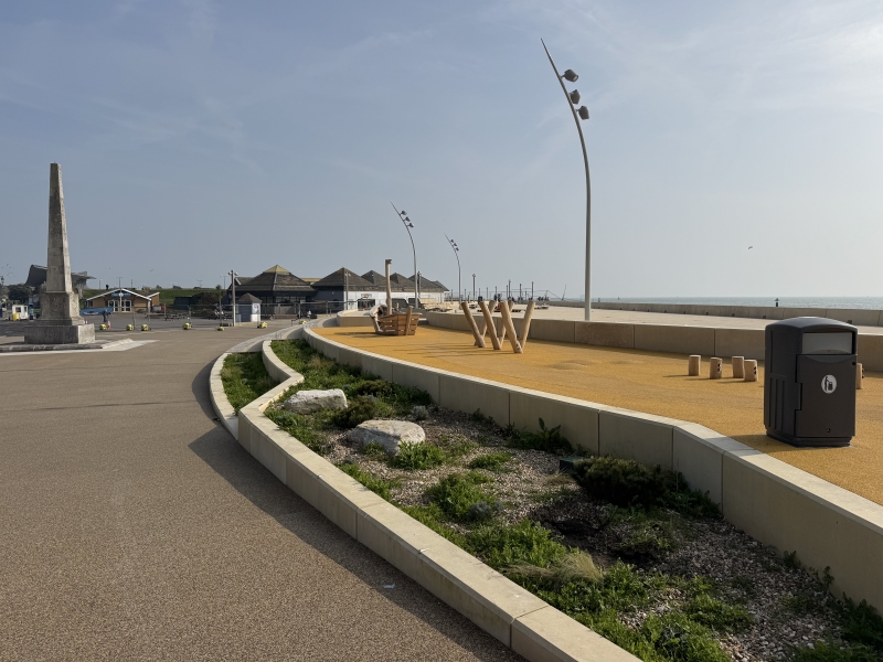 Promenade with play area, a monument to the left with blue skies