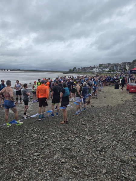 group of people stood on a pebble beach. Grey skies