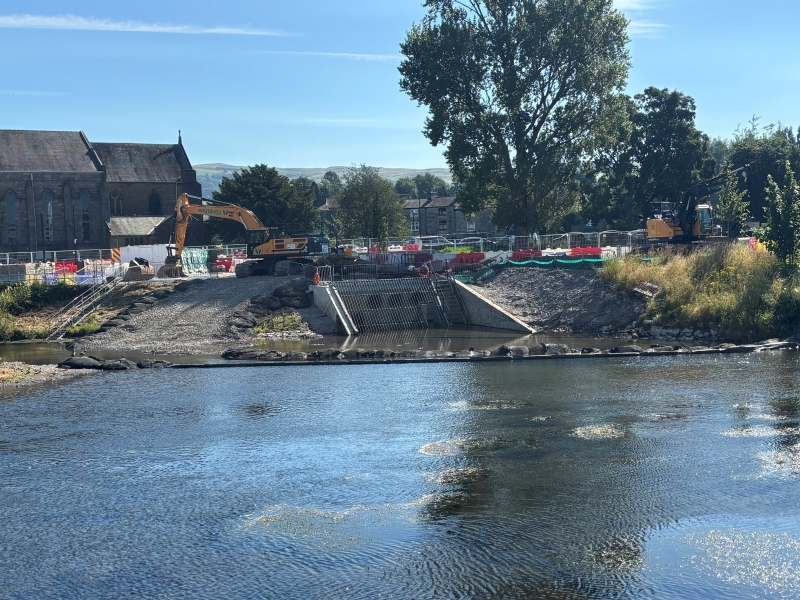river in the foreground and construction taking place in the background on the river bank