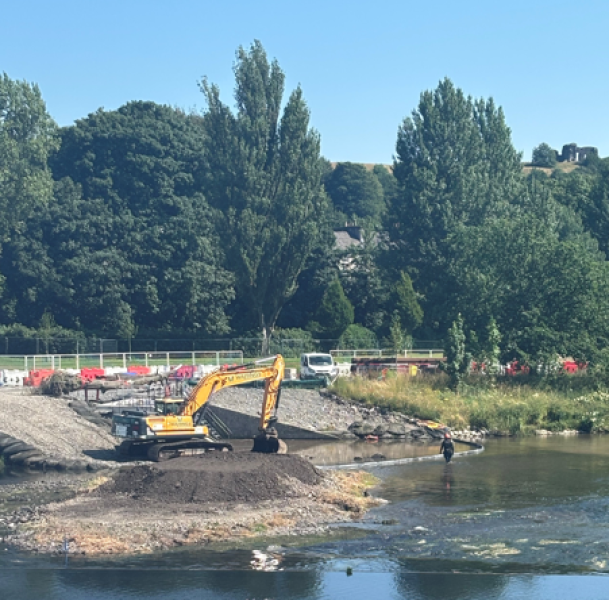 yellow digger on the rover back with river in the foreground