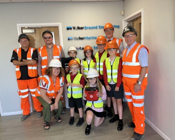 Children in high vis receiving a defibrillator.