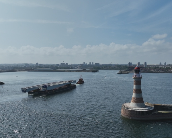 bridge section on barge travelling on water out of a port