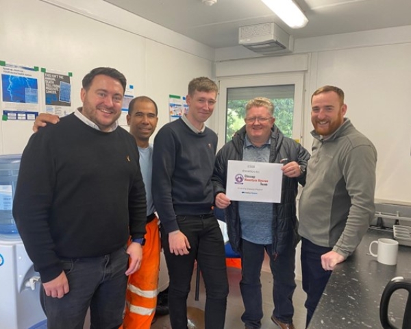 People stood in a kitchen holding a certificate. 
