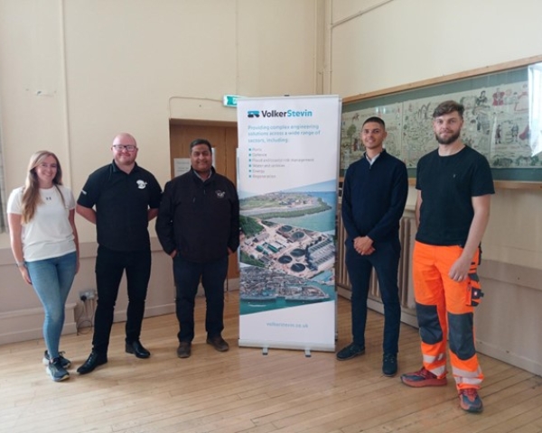 People smiling stood next to a VolkerStevin banner. 