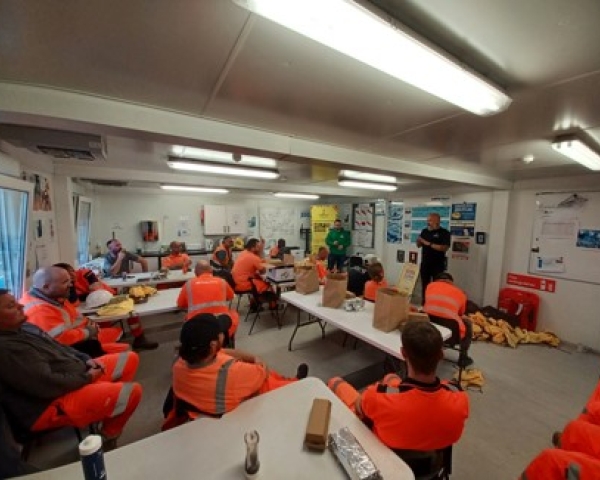 People sat in a room listening to someone talk.