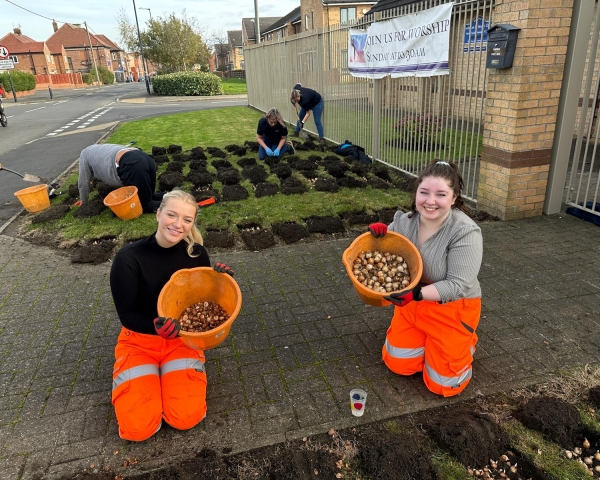 Two girls knelt down holding buckets of bulbs.