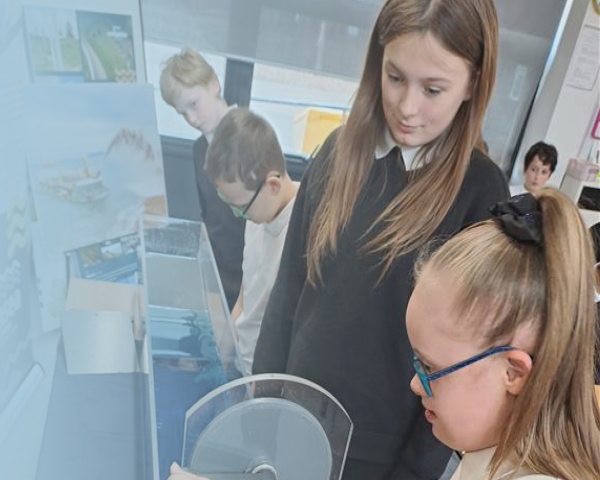 Children stood up doing a demonstration with a water tank