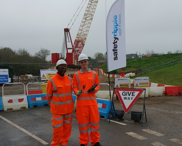 Two men in PPE stood in front of a crane.