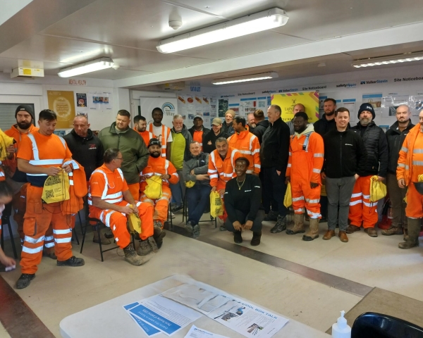Group of people stood in a huddle, smiling at the camera.